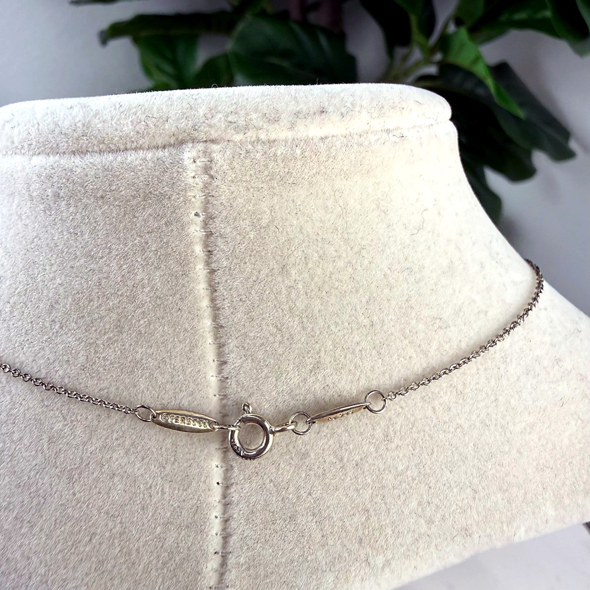 Clasp detail of Tiffany & Co. Elsa Peretti necklace showing PERETTI signature tag and sterling silver purity mark