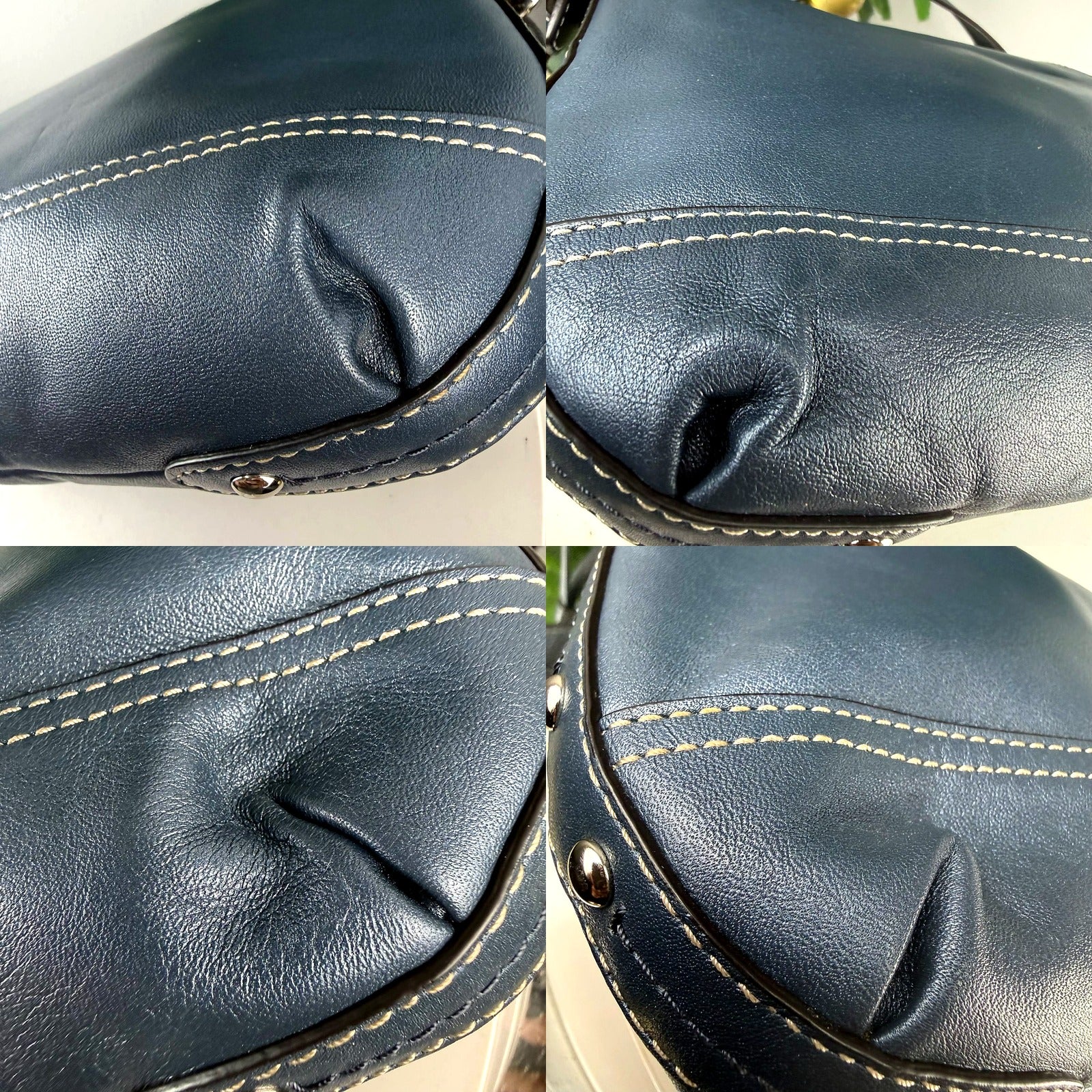 Coach navy shoulder bag close-up of leather creasing and light crackling at base corner