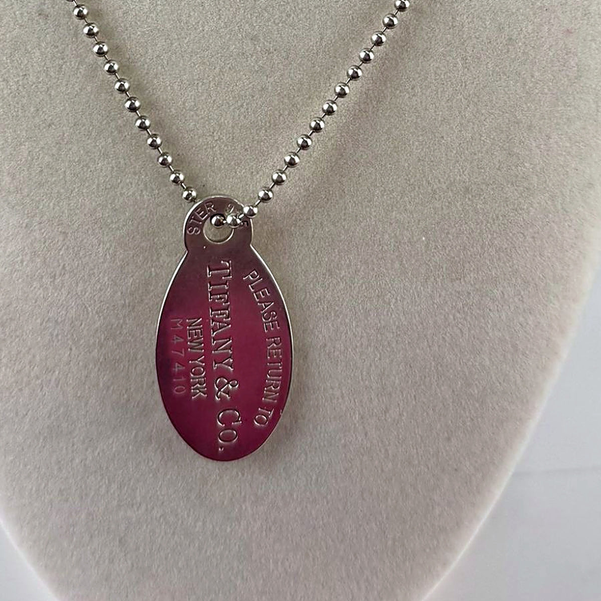 Close-up of Tiffany & Co. Return to Tiffany oval tag engraving reading PLEASE RETURN TO TIFFANY & CO. NEW YORK M47410