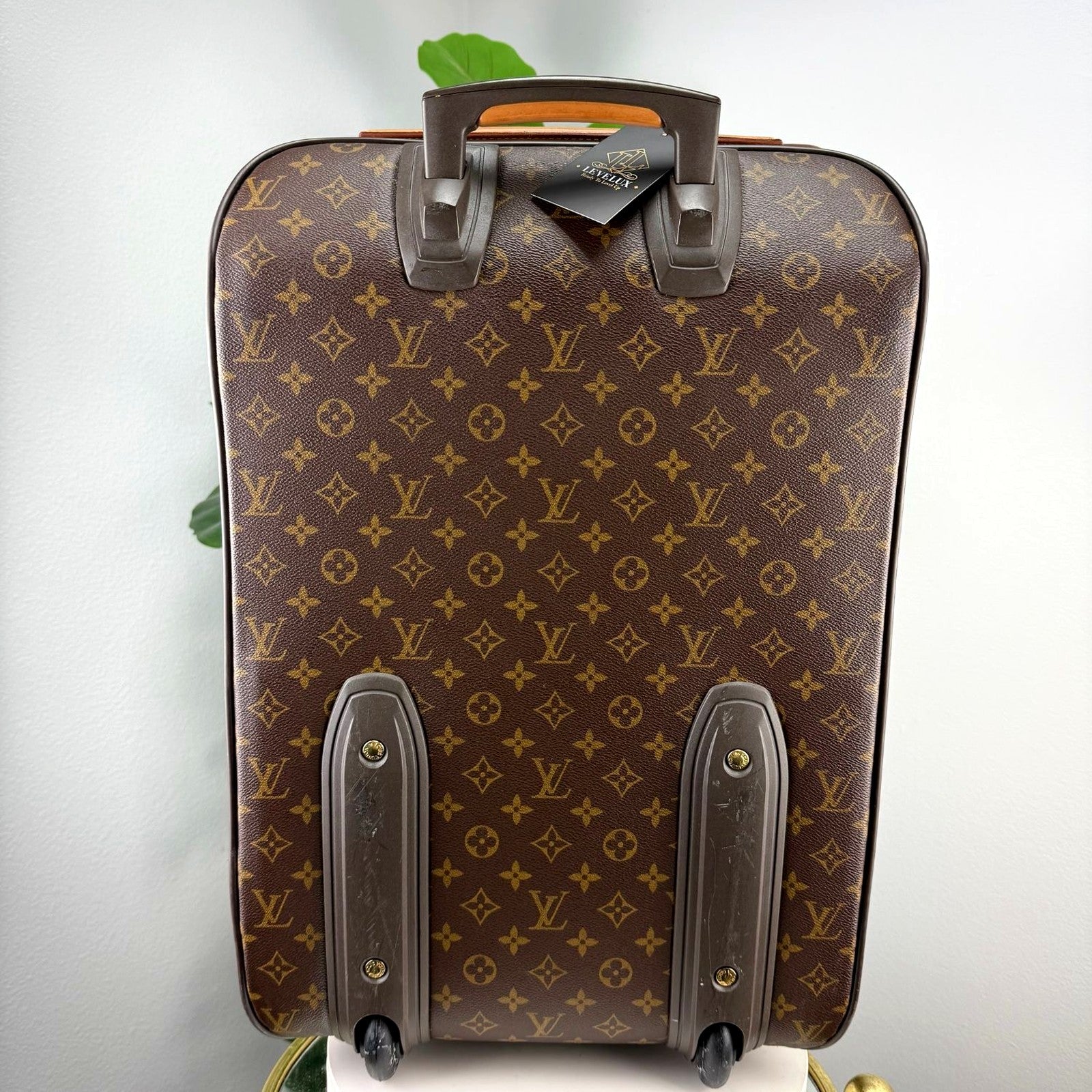 Louis Vuitton Pegase suitcase back view with retractable handle, wheels, and LeveLux hangtag