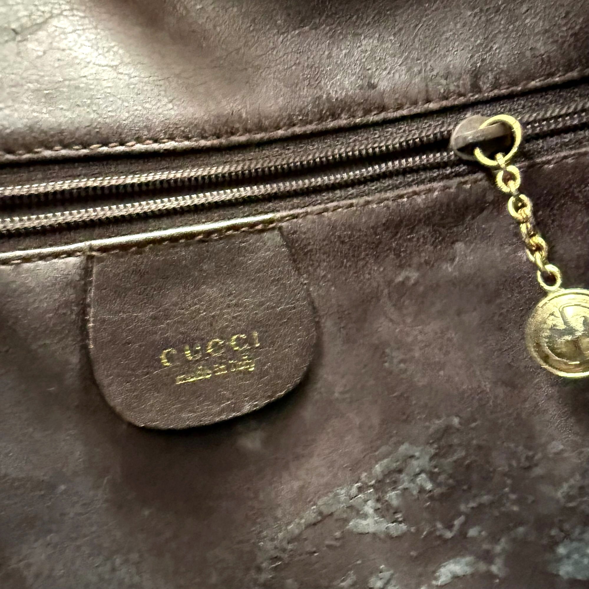 Macro shot of Gucci Made in Italy stamped leather tag and gold zipper charm