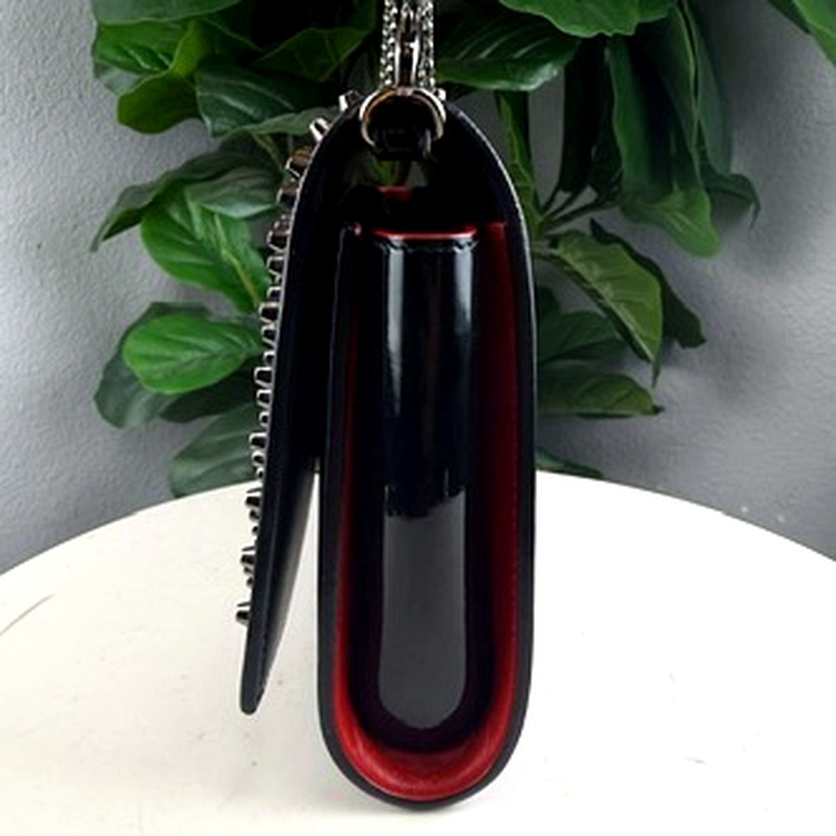 Christian Louboutin spike clutch side view showing red trim